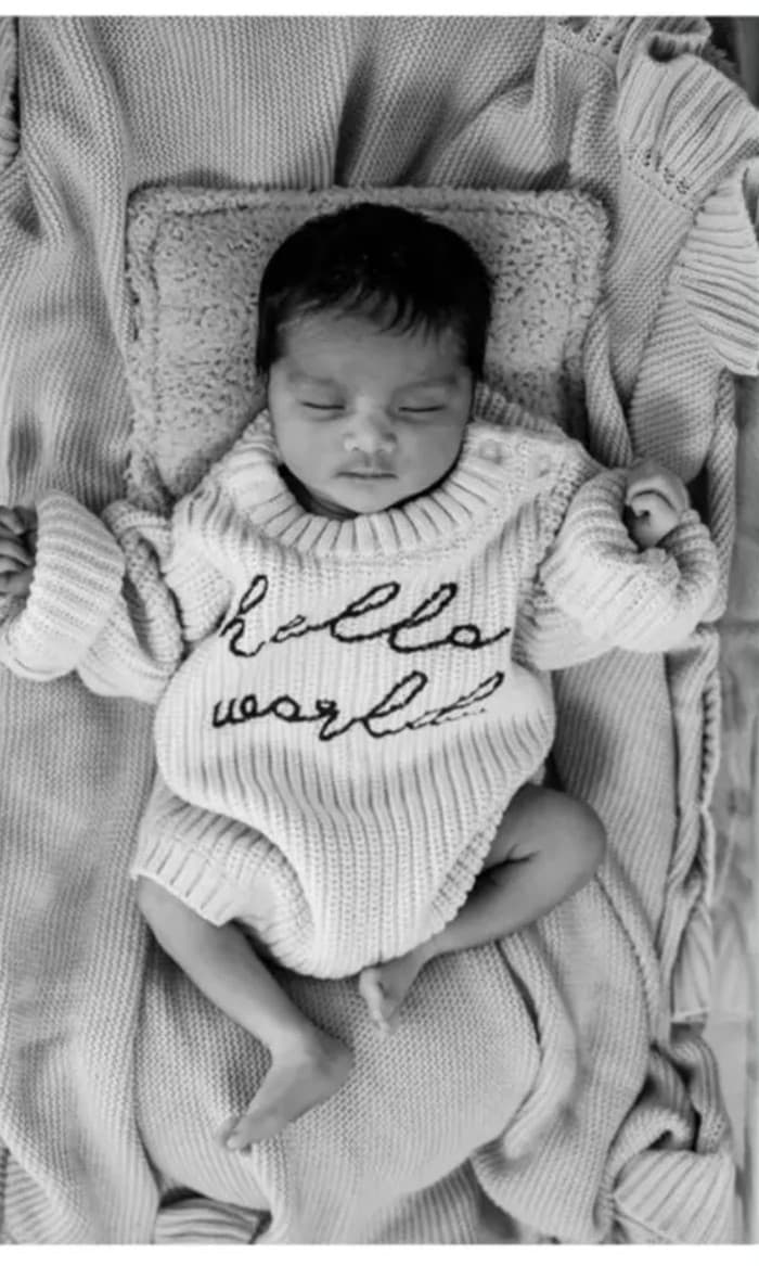 Newborn baby wearing Hello World knitted romper, black and white photo